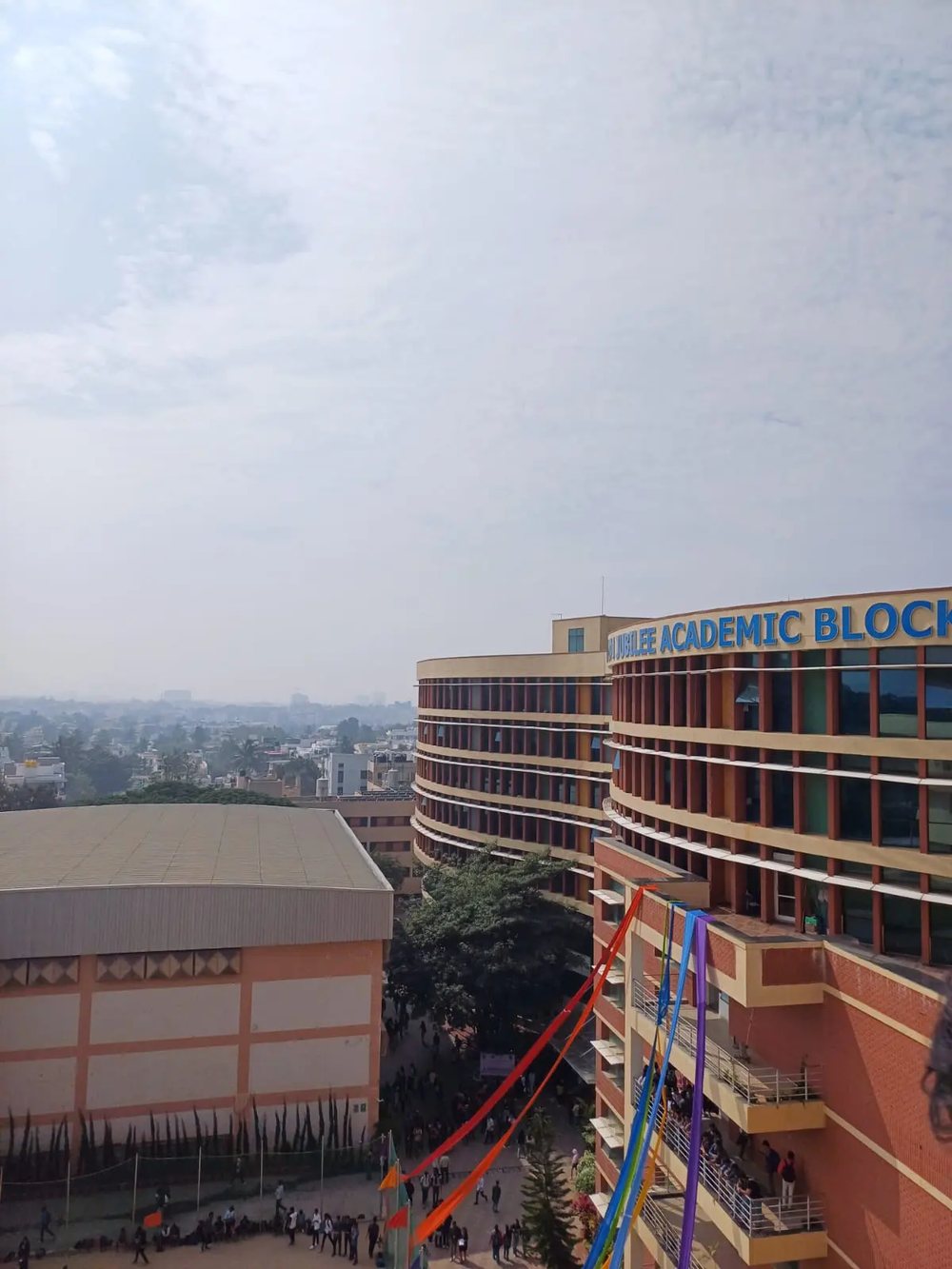 The curved Jubilee Academic Block at BMSCE above the campus, with ribbons strung from its balconies